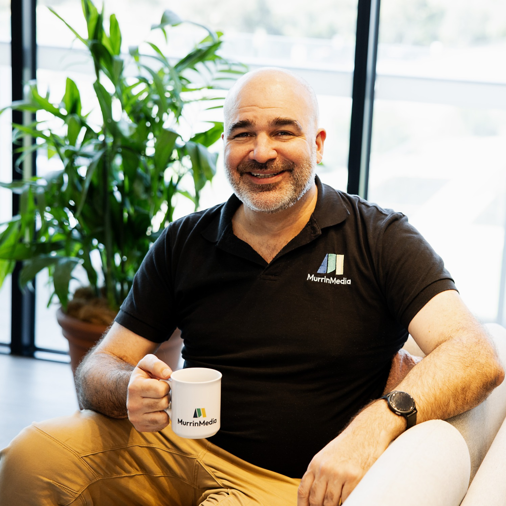Man smiling with coffee mug indoors.