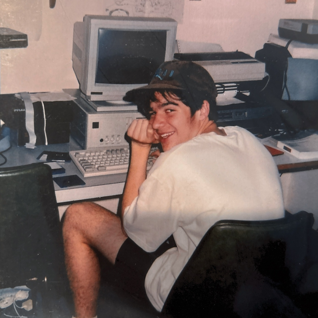 Smiling person at vintage computer desk.